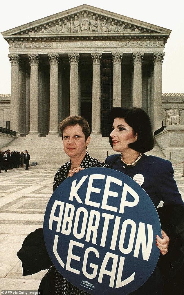 Norma McCorvey (left)  holds a pro-choice sign with former attorney Gloria Allred (right) in front of the US Supreme Court building on April 26, 1989