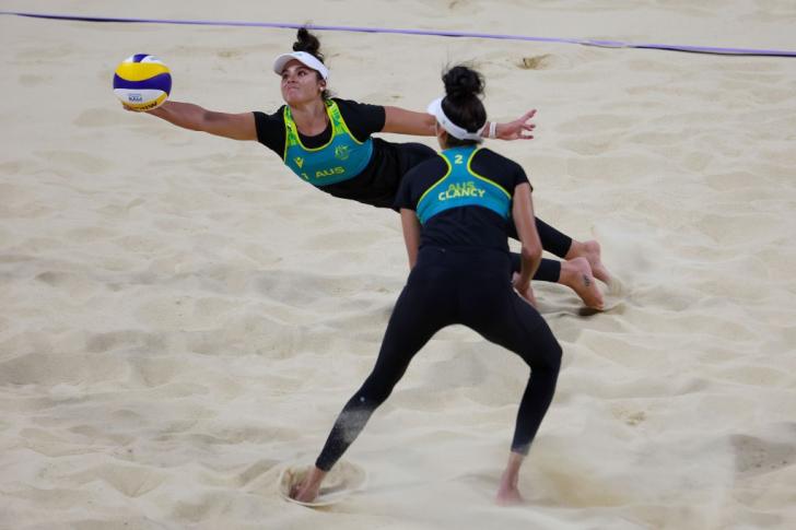 beach volleyball players in action reaching for ball