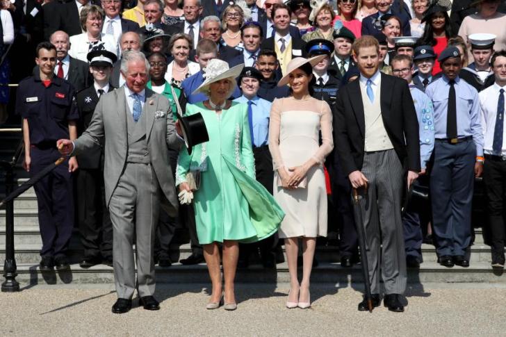 King Charles, Queen Camilla, Meghan Markle and Prince Harry walking in front of a crowd.
