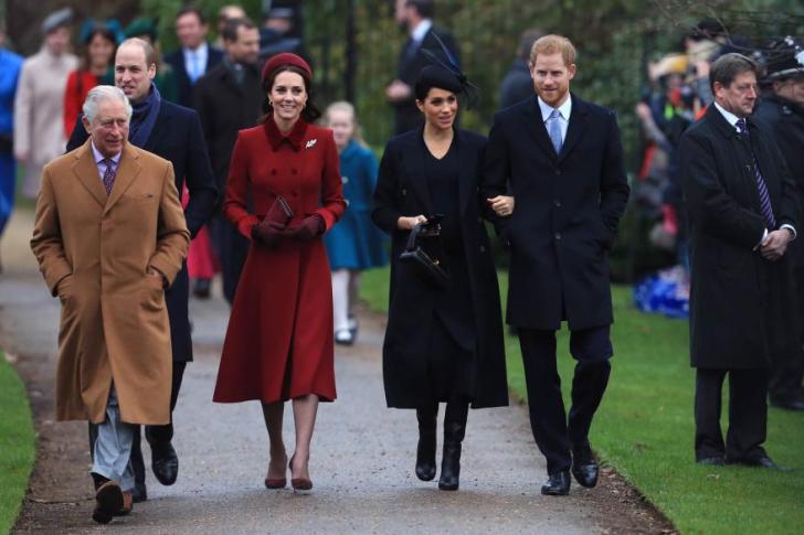 King Charles, Prince William, Kate Middleton, Meghan Markle and Prince Harry walking outside together.