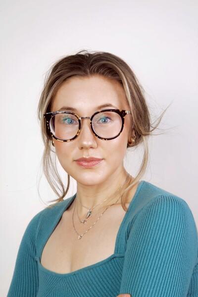 Headshot of a young woman in a teal top with glasses
